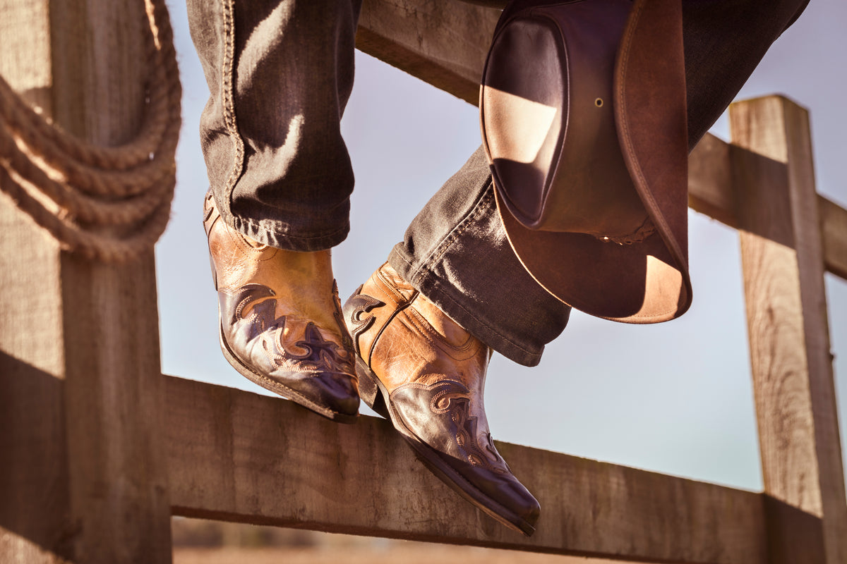 Western boots resting on a timber fence